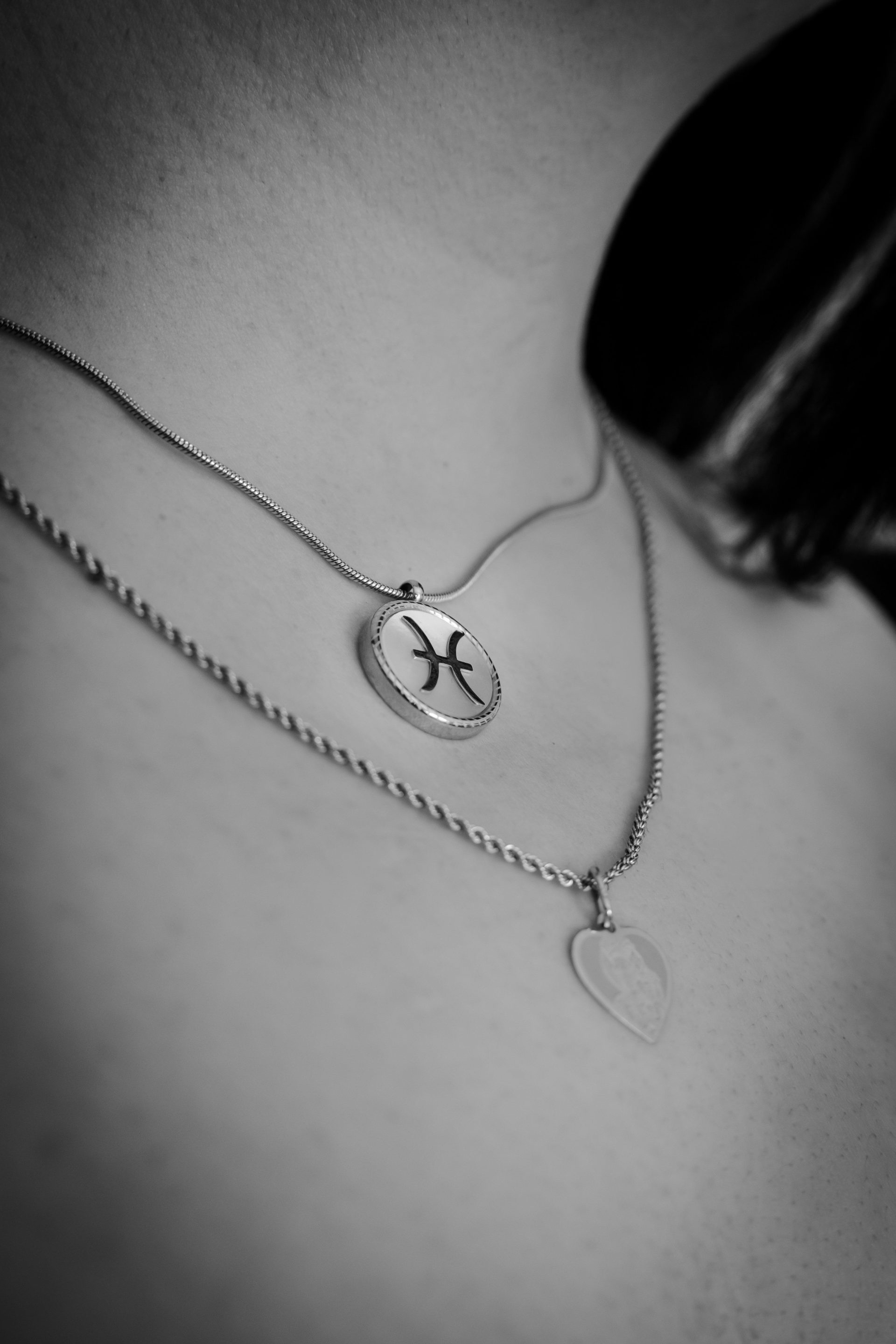 Two silver necklaces worn by a person.
